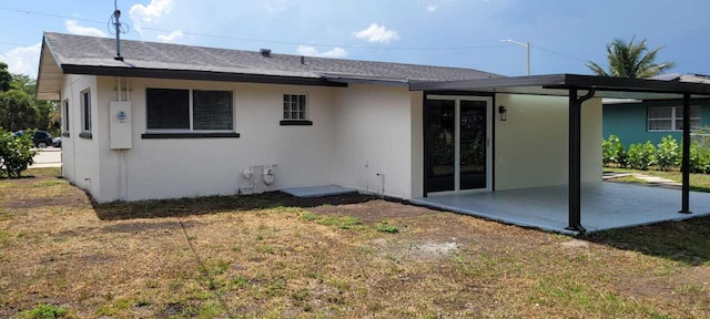 rear view of house featuring a lawn, a patio, and stucco siding