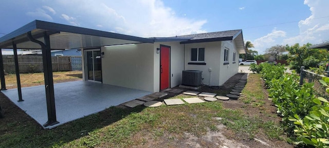 view of outbuilding featuring central AC, an attached carport, and fence