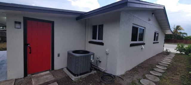 view of property exterior with stucco siding, fence, and central AC