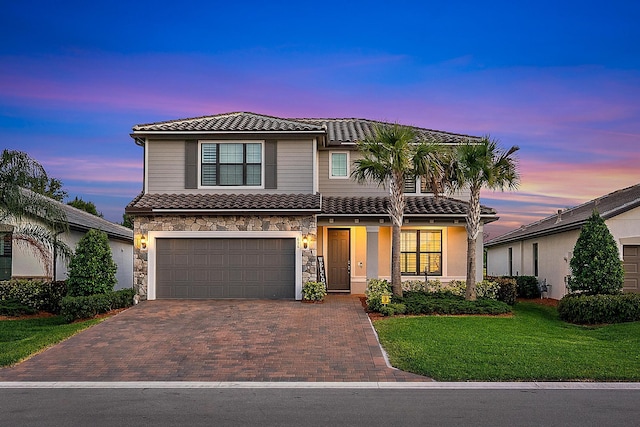 656 SE Villandry Way, Port Saint Lucie, FL 34984 - view of front of house featuring a tile roof, a garage, decorative driveway, a front yard, and stone siding