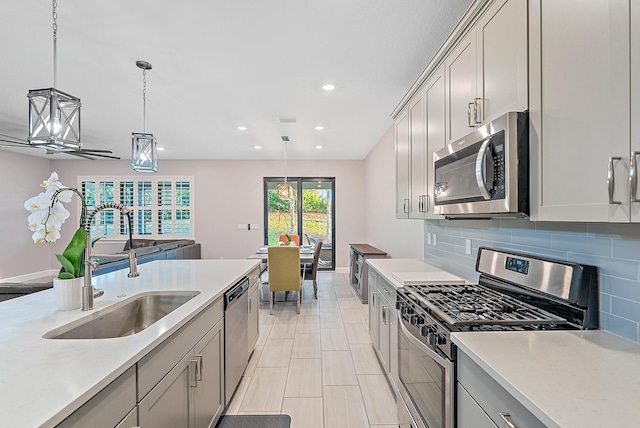 656 SE Villandry Way, Port Saint Lucie, FL 34984 - kitchen with appliances with stainless steel finishes, a sink, light countertops, tasteful backsplash, and hanging light fixtures