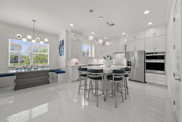 5651 Macoon Way, Westlake, FL 33470 - kitchen with appliances with stainless steel finishes, crown molding, white cabinets, a kitchen bar, and light countertops