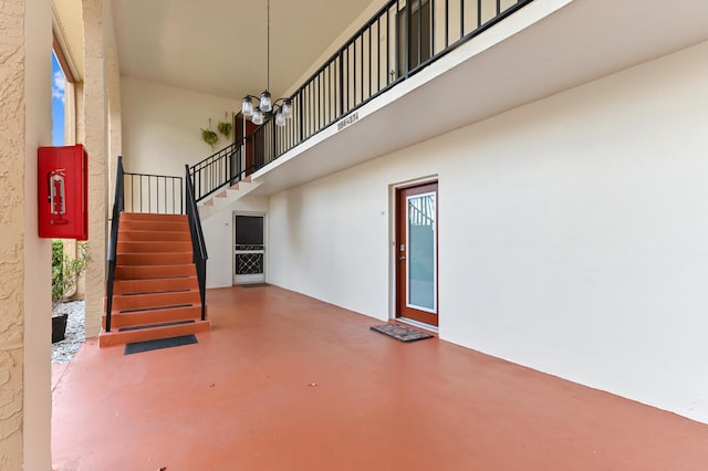 stairs featuring a chandelier, finished concrete floors, and a towering ceiling