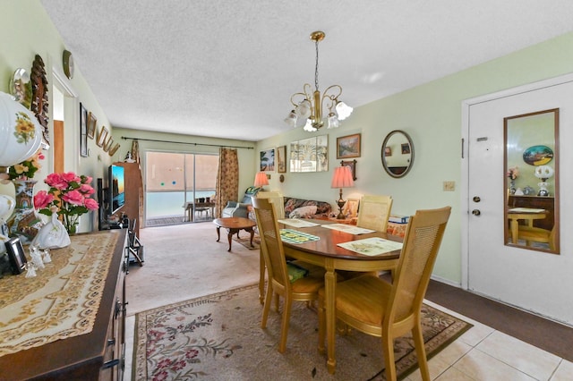 dining space with a chandelier, light colored carpet, a textured ceiling, and light tile patterned flooring