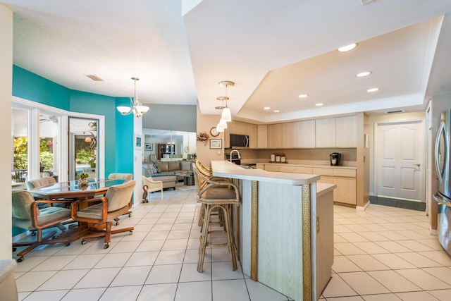 kitchen with recessed lighting, a breakfast bar, a peninsula, light countertops, and appliances with stainless steel finishes