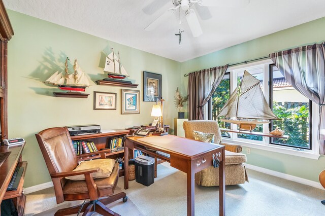 carpeted office with baseboards and a ceiling fan