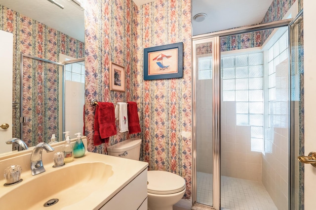 full bathroom featuring wallpapered walls, toilet, a shower stall, and vanity