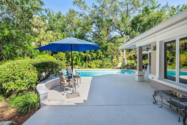 outdoor pool with ceiling fan and a patio