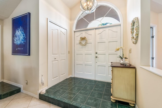 entryway with dark tile patterned flooring, baseboards, and a notable chandelier