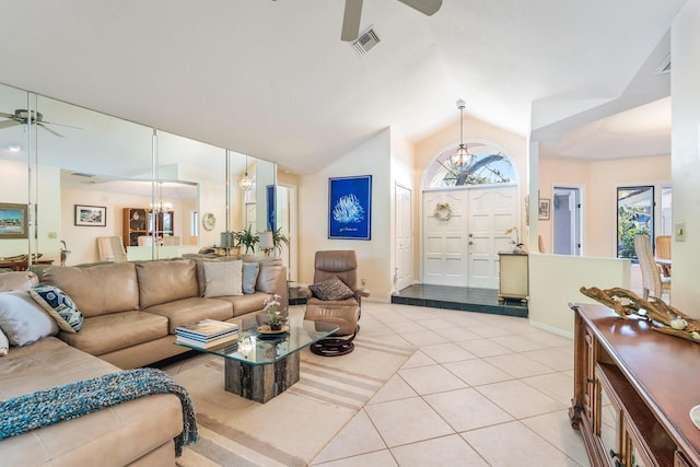 living area featuring lofted ceiling, light tile patterned floors, visible vents, and ceiling fan with notable chandelier
