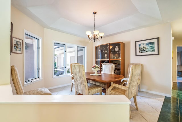 dining room with a tray ceiling, an inviting chandelier, baseboards, and light tile patterned flooring