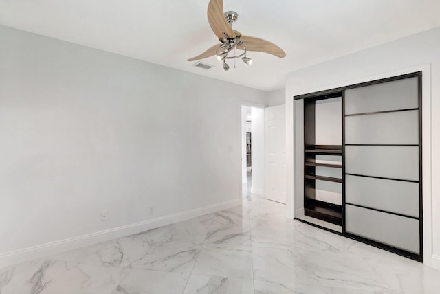 spare room featuring light marble finish flooring, baseboards, and ceiling fan