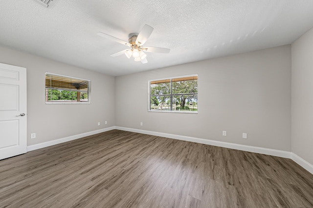 unfurnished room featuring plenty of natural light, wood finished floors, ceiling fan, baseboards, and a textured ceiling