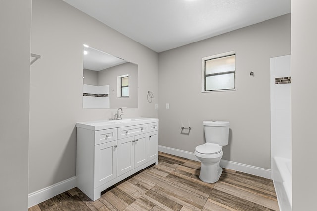 bathroom featuring toilet, vanity, baseboards, and wood finished floors