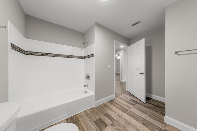 full bath featuring toilet, wood finished floors, shower / bathtub combination, and baseboards
