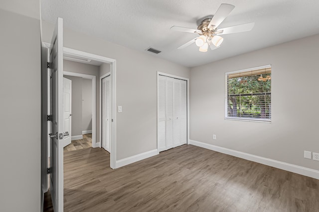 unfurnished bedroom featuring wood finished floors, baseboards, ceiling fan, and a closet