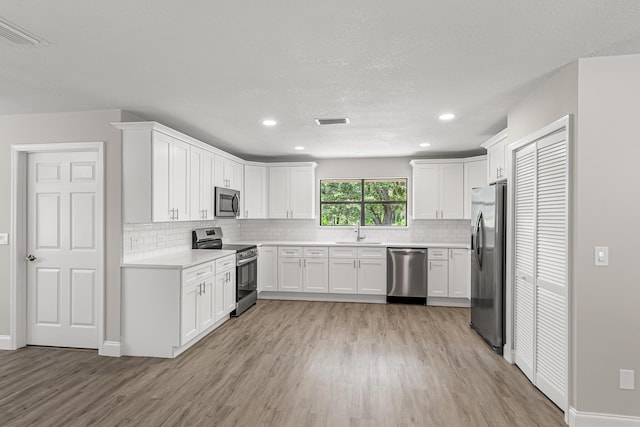 kitchen with stainless steel appliances, a sink, light wood-style flooring, decorative backsplash, and recessed lighting