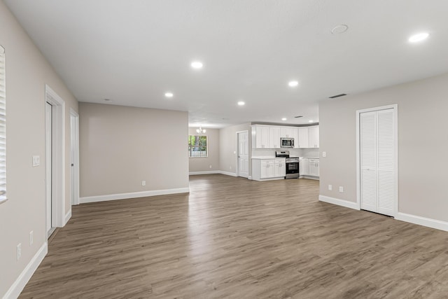 unfurnished living room with recessed lighting, baseboards, and wood finished floors