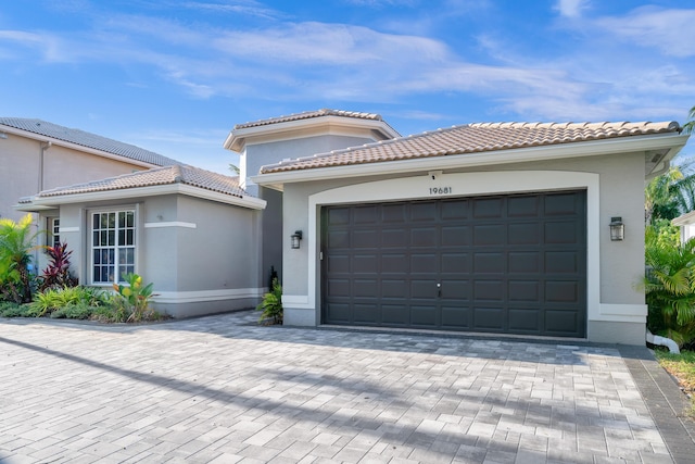 view of front facade featuring a garage, stucco siding, decorative driveway, and a tile roof
