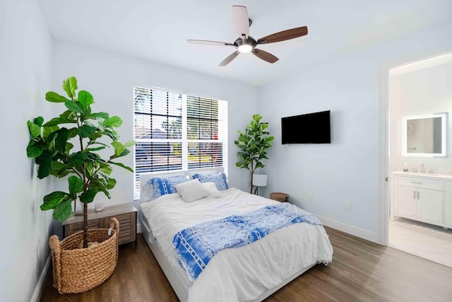 bedroom with wood finished floors, a sink, baseboards, connected bathroom, and ceiling fan
