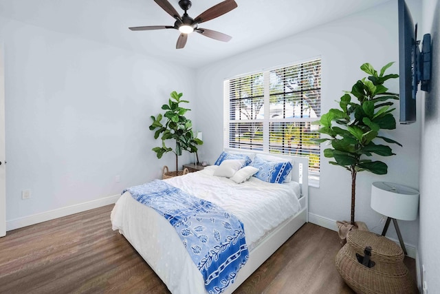 bedroom featuring wood finished floors, multiple windows, baseboards, and a ceiling fan