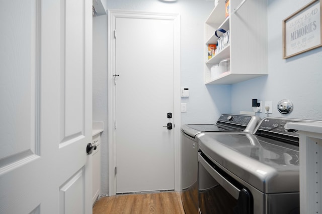 washroom featuring washer and clothes dryer, cabinet space, and light wood-style floors