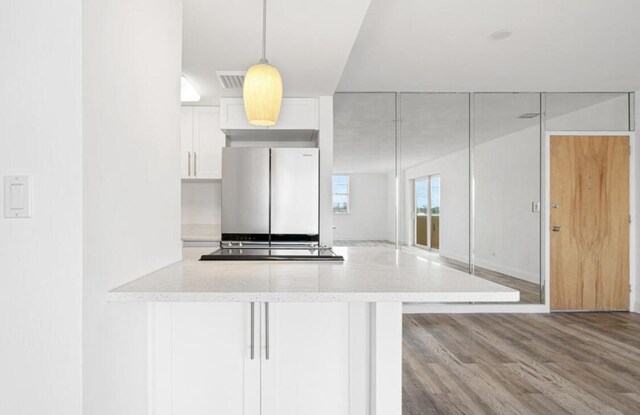 2800 N Flagler Dr Unit 410, West Palm Beach, FL 33407 - kitchen with freestanding refrigerator, white cabinetry, light stone counters, and wood finished floors