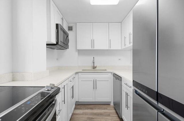 2800 N Flagler Dr Unit 410, West Palm Beach, FL 33407 - kitchen with a sink, stainless steel appliances, light wood-type flooring, white cabinetry, and light countertops