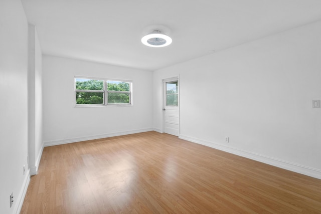 empty room with plenty of natural light, light wood-style floors, and baseboards