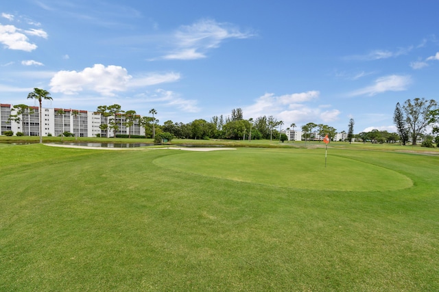 view of property's community with golf course view, a water view, and a lawn