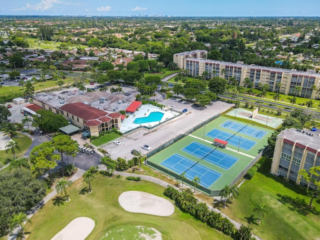 drone / aerial view of a golf club, apartment complex / building, and a pool area