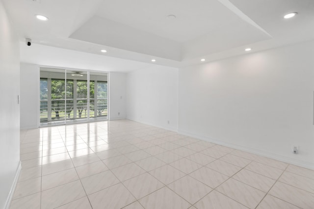 spare room with recessed lighting, baseboards, and a raised ceiling