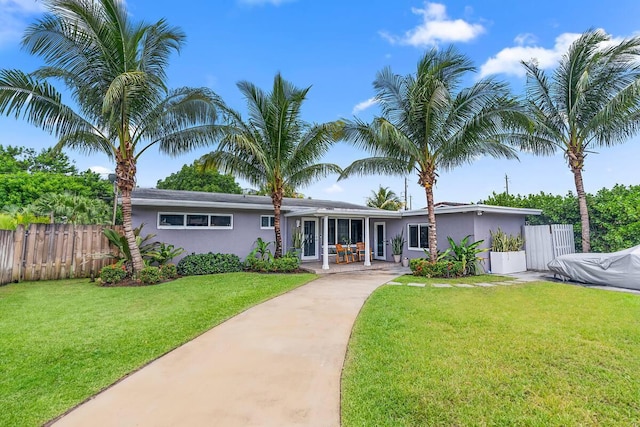 ranch-style home featuring a front lawn, concrete driveway, stucco siding, and fence
