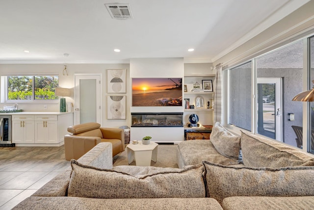 living area with indoor wet bar, ornamental molding, light tile patterned flooring, visible vents, and beverage cooler