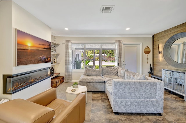 living room with ornamental molding, wooden walls, a glass covered fireplace, and recessed lighting