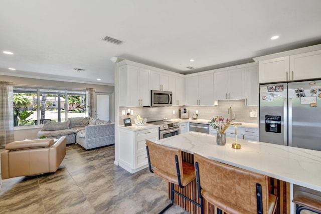 kitchen featuring decorative backsplash, open floor plan, visible vents, and appliances with stainless steel finishes