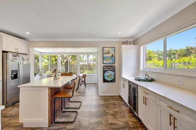 kitchen with beverage cooler, a breakfast bar, white cabinetry, crown molding, and stainless steel refrigerator with ice dispenser