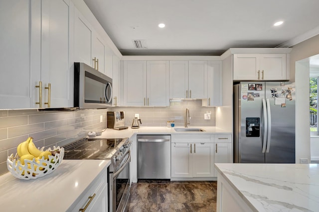 kitchen with a sink, stainless steel appliances, white cabinetry, visible vents, and tasteful backsplash
