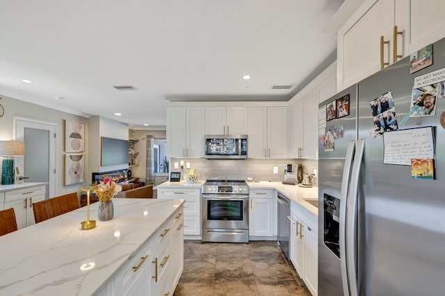 kitchen with visible vents, backsplash, white cabinets, light stone countertops, and appliances with stainless steel finishes