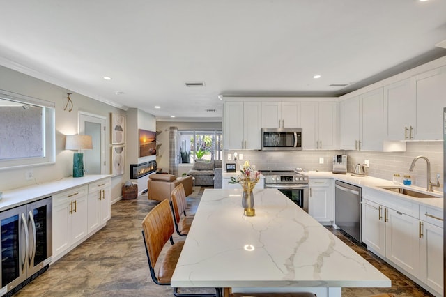 kitchen featuring beverage cooler, visible vents, a sink, white cabinets, and appliances with stainless steel finishes