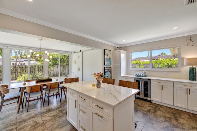 kitchen with a notable chandelier, beverage cooler, visible vents, a kitchen island, and white cabinets