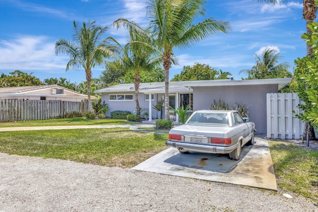 ranch-style house with a front lawn, stucco siding, and fence