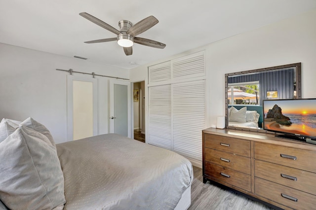 bedroom with light wood finished floors, a closet, visible vents, and ceiling fan