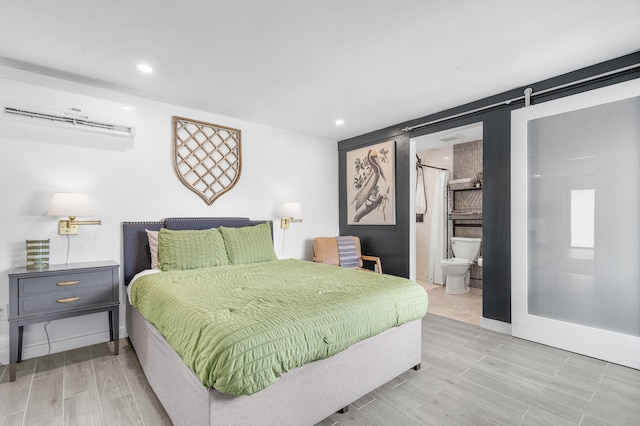 bedroom featuring wood tiled floor, recessed lighting, a barn door, a wall mounted AC, and baseboards