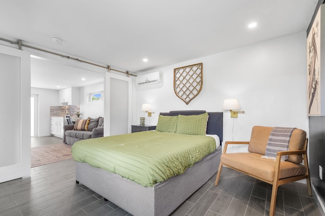 bedroom with wood tiled floor, recessed lighting, a barn door, a wall mounted AC, and baseboards