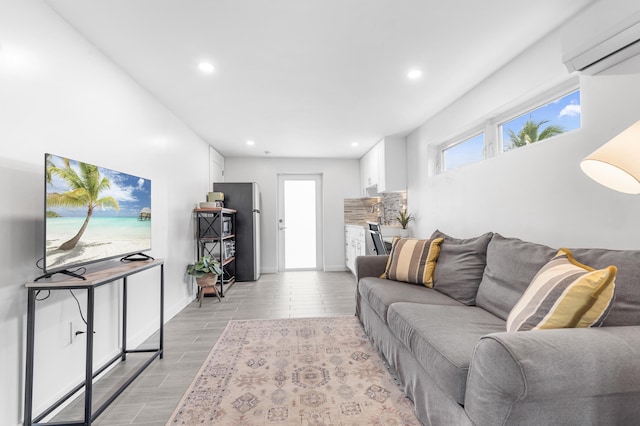 living room featuring light wood-type flooring, baseboards, a wall unit AC, and recessed lighting