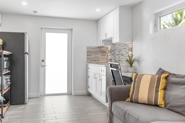 living area featuring light wood-style flooring, wet bar, baseboards, and recessed lighting