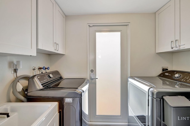 washroom with washing machine and clothes dryer, a sink, and cabinet space