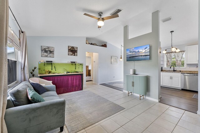 living area with lofted ceiling, a ceiling fan, light tile patterned floors, a chandelier, and baseboards