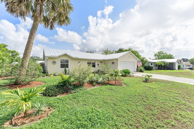 ranch-style house featuring driveway, an attached garage, a front yard, and metal roof